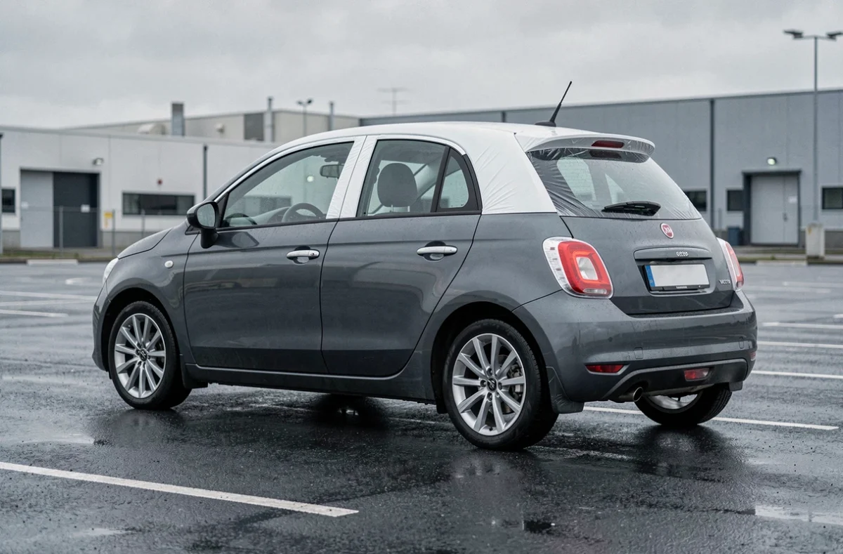 Voiture compacte avec toit et rétroviseurs en covering blanc contrastant avec la carrosserie gris foncé