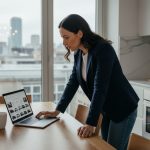 Les nouvelles habitudes d’achat automobile en ligne Femme en blazer comparant voitures en intérieur lumineux