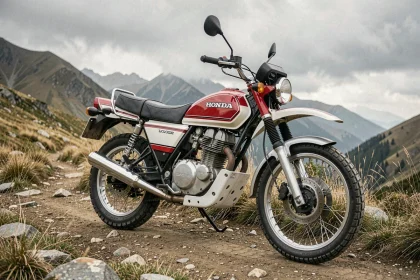 Honda XLV750R rouge et blanc garée sur une piste de montagne rocailleuse, vue grand angle mettant en valeur son moteur V-twin et ses pneus tout-terrain