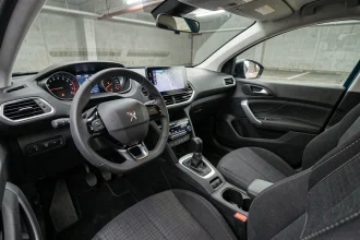 Tableau de bord de la Peugeot 308 version entrée de gamme, vue depuis le siège passager avec écran tactile central et volant i-Cockpit