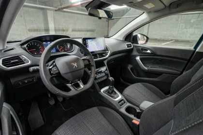 Tableau de bord de la Peugeot 308 version entrée de gamme, vue depuis le siège passager avec écran tactile central et volant i-Cockpit