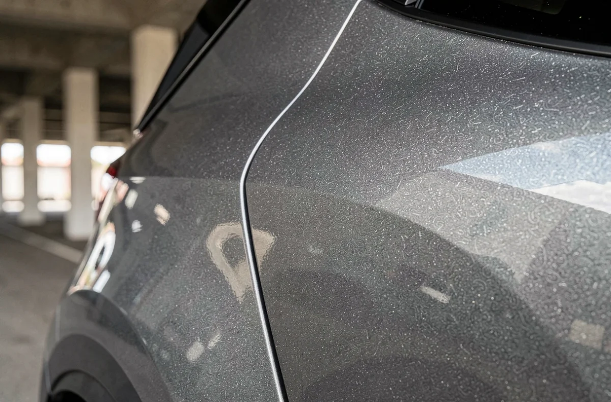 Gros plan sur la teinte gris rafale de la carrosserie du Renault Symbioz, révélant la profondeur des pigments métalliques et l'aspect laqué
